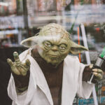 Paris, France - April 28, 2016: Portrait of Jedi Master Yoda toy model with green lightsaber on window display in Paris. Yoda is a fictional character in the Legend Star Wars Film franchise created by director George Lucas